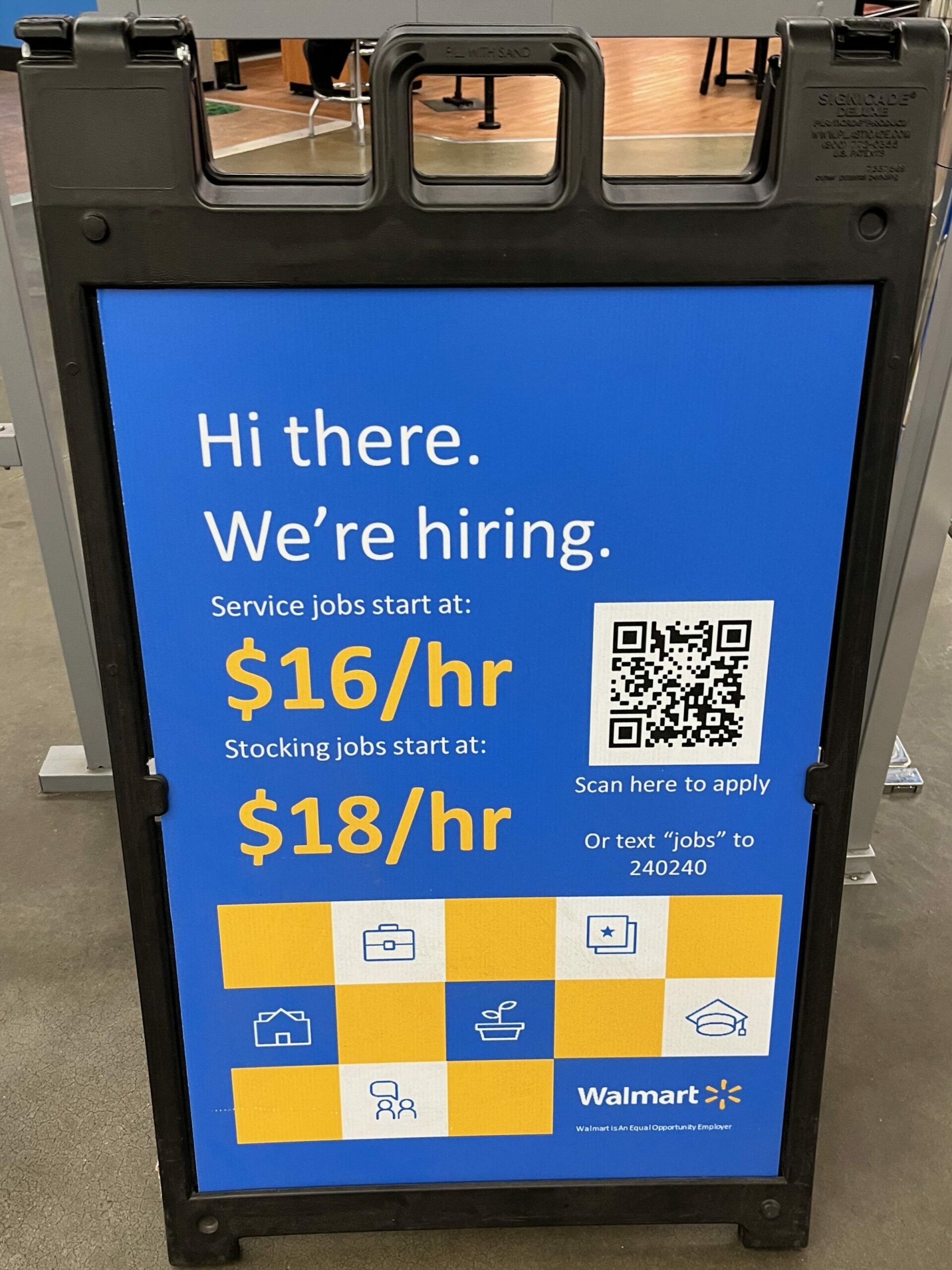 A Walmart sandwichboard style sign advertising service jobs starting at $16/hr and stocking jobs starting at $18/hr. It's located inside a Walmart store.